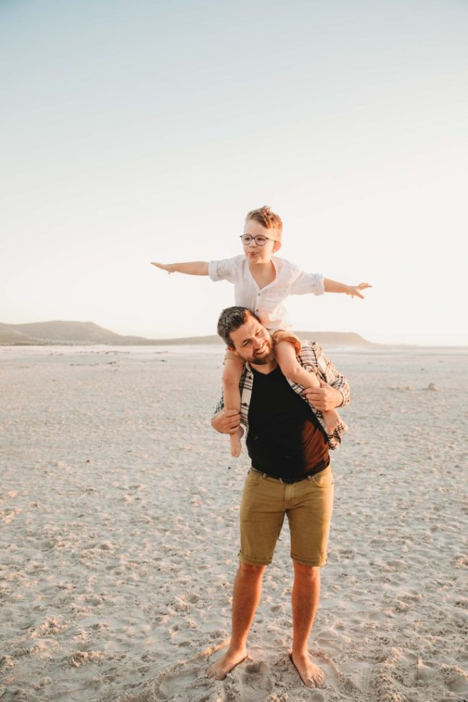 father and son in the aeroplane pose on a beach