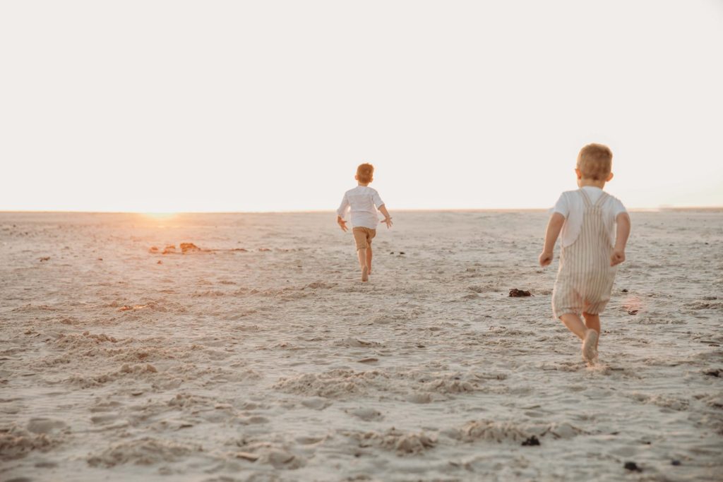 Young children laughing and playing in sand during family photo session in Cape Town