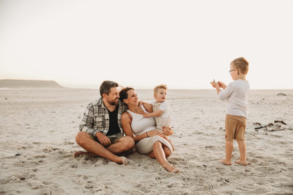 Young children laughing and playing in sand during family photo session in Cape Tow
