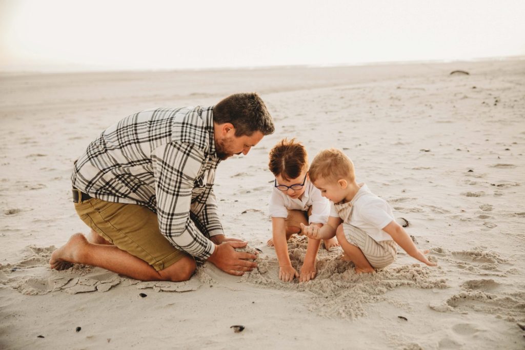 father and kids playing in the sand on noordhoek beach