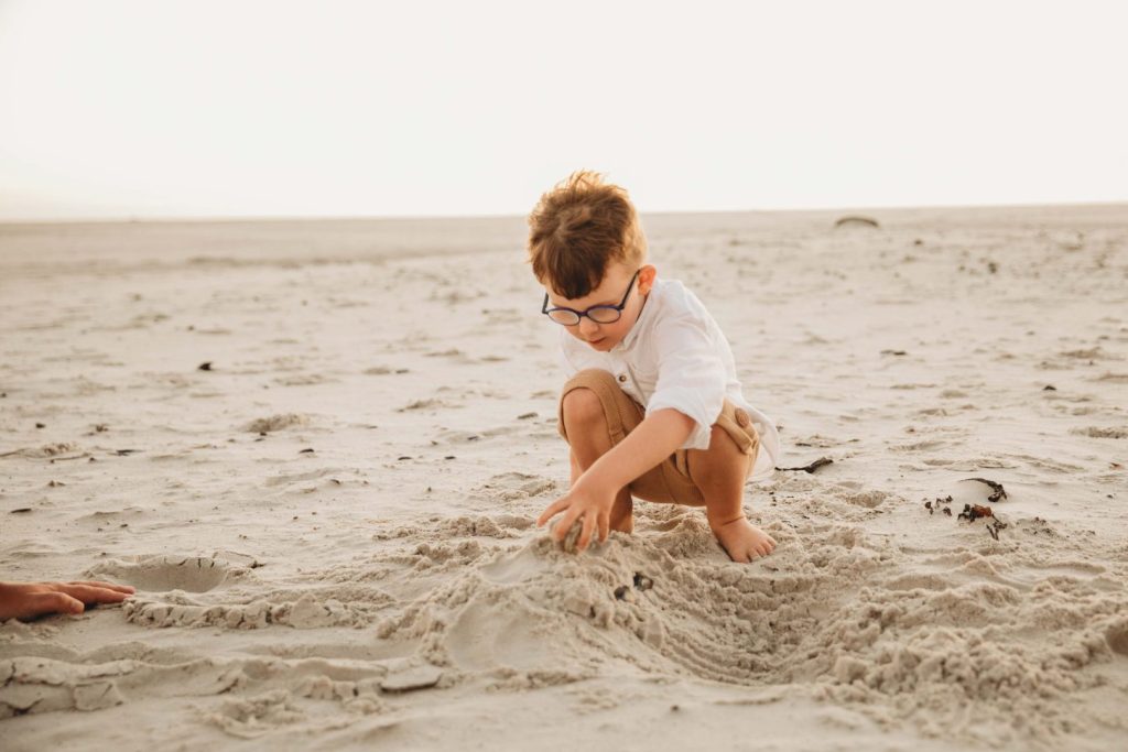 Young children laughing and playing in sand during family photo session in Cape Tow