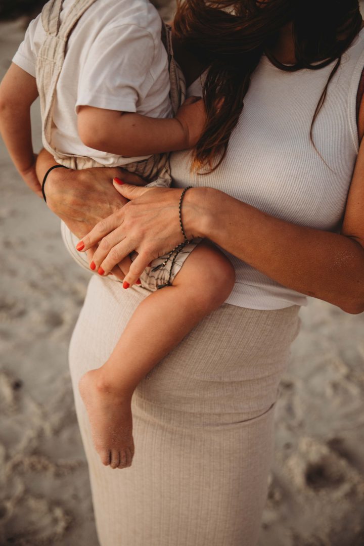 pregnant mom embracing her son displaying her pregnant tummy at sunset