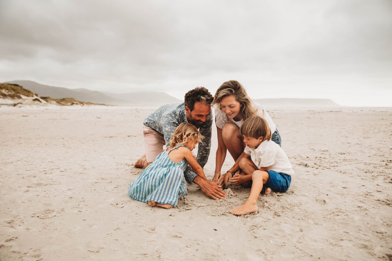 family playing on noordhoek beach building sand castles