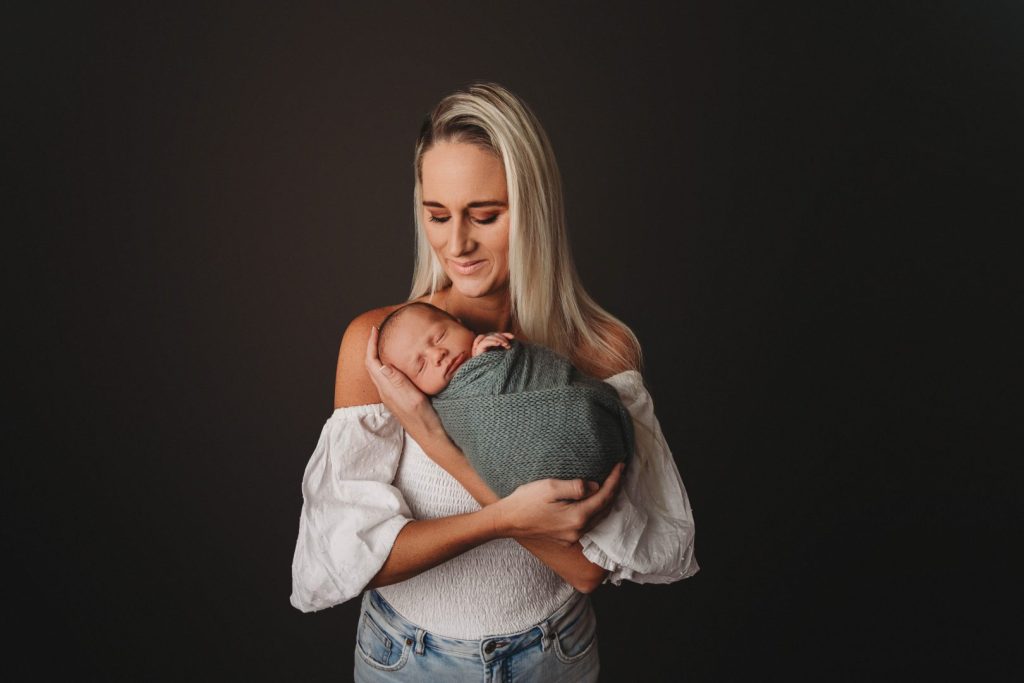 Studio portrait of a newborn baby held by mom in a photo shoot