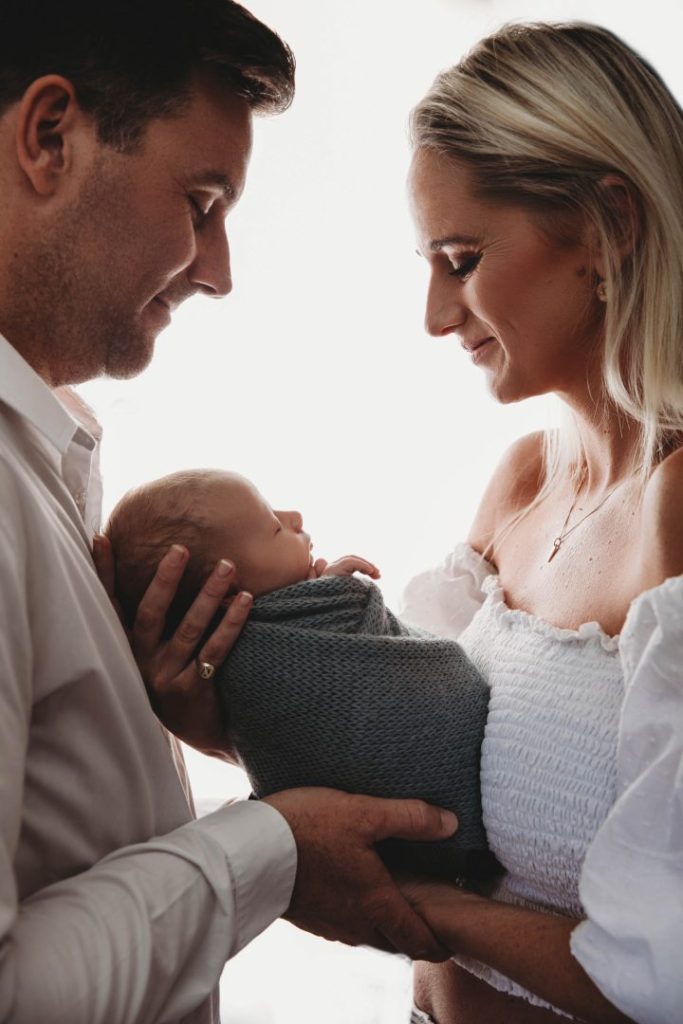 newborn baby held by parents in silouette newborn photo shoot