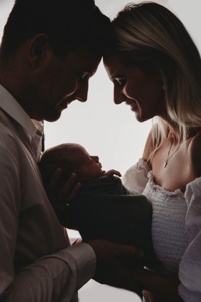 newborn baby held by parents in silouette newborn photo shoot