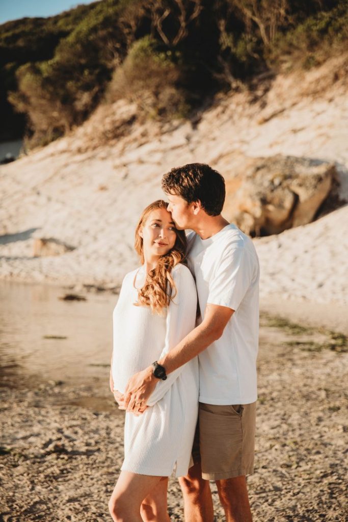 Candid maternity moment with couple embracing on Noordhoek Beach, Cape Town