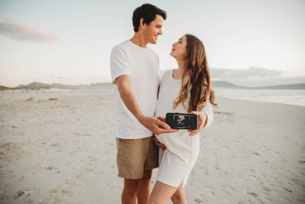 Candid maternity moment with couple embracing on Noordhoek Beach, Cape Town