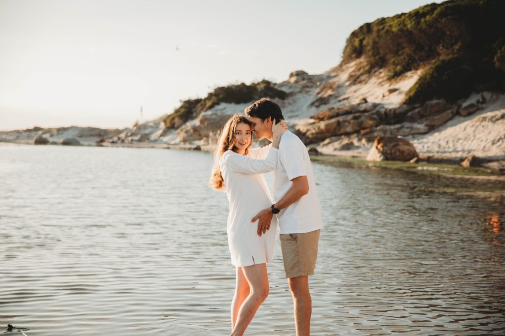 Candid maternity moment with couple embracing on Noordhoek Beach, Cape Town