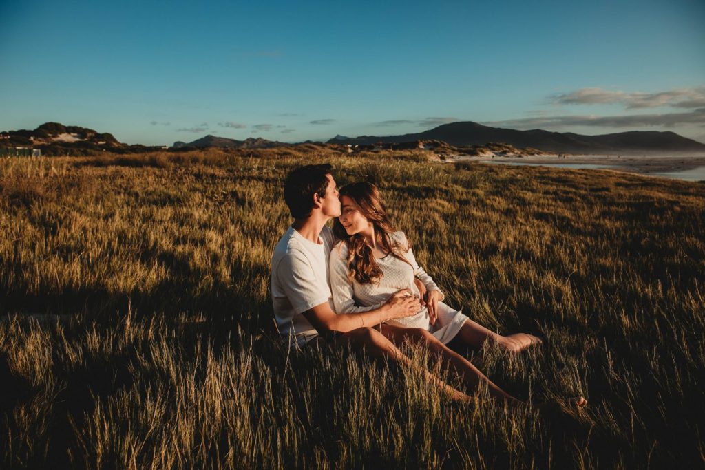 Expectant mother posing on Noordhoek dunes with ocean in the background