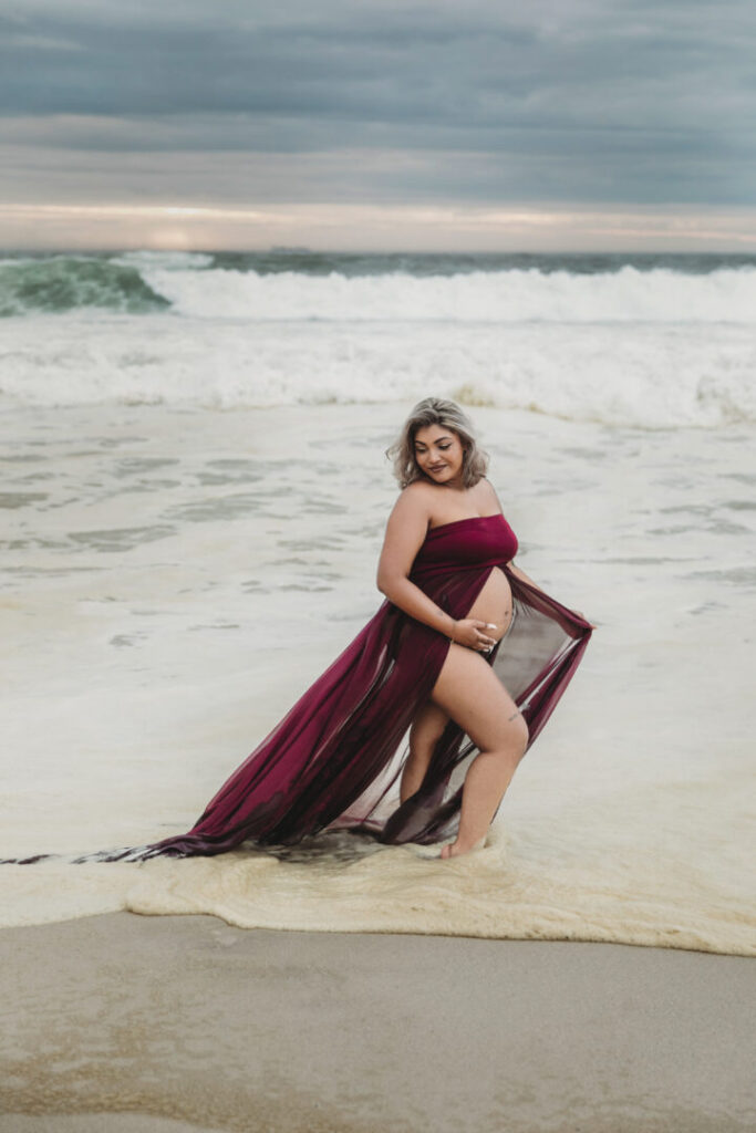 Cape Town maternity photographer photographing a pregnant woman in a flowing purple dress at Llandudno Beach