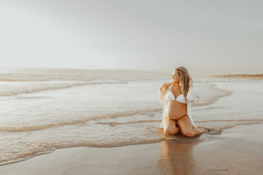 pregnant mom in the ocean wearing white at sunset