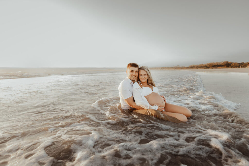 pregnant couple in the ocean during maternity photo shoot