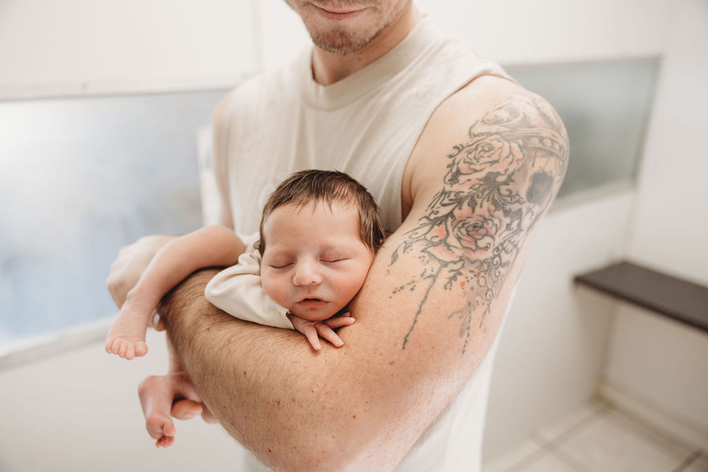 newborn baby in dads arms during photo shoot