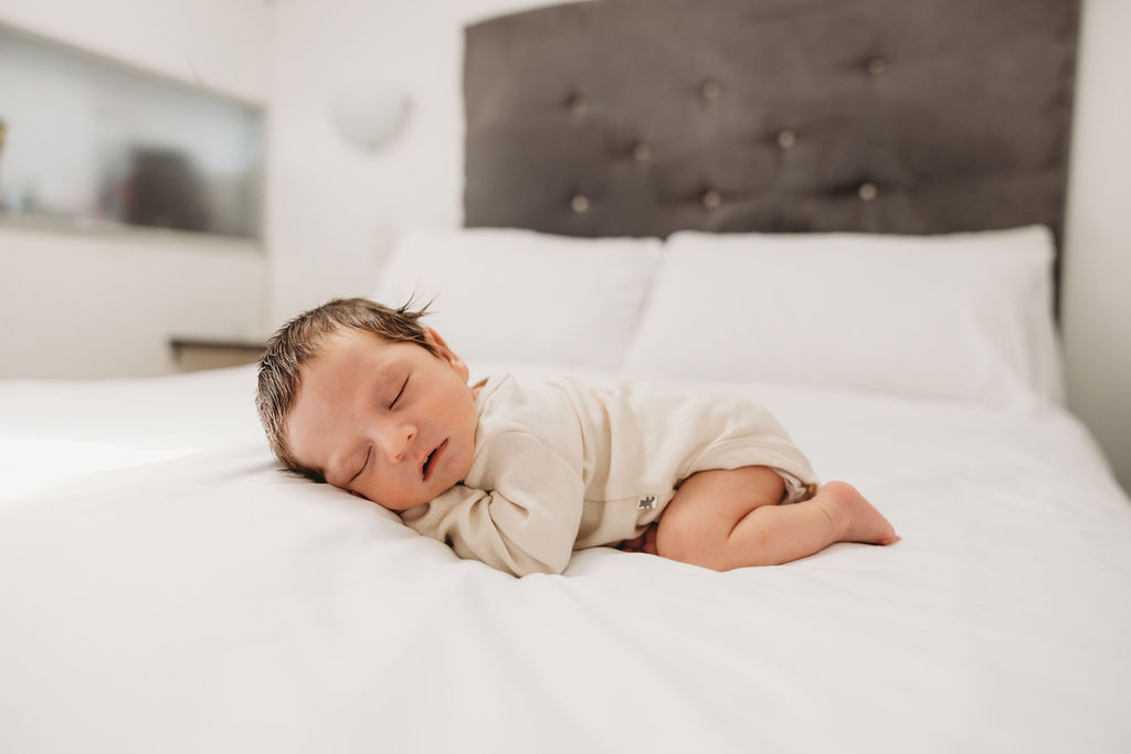 colour photo of baby on king size bed sleeping 