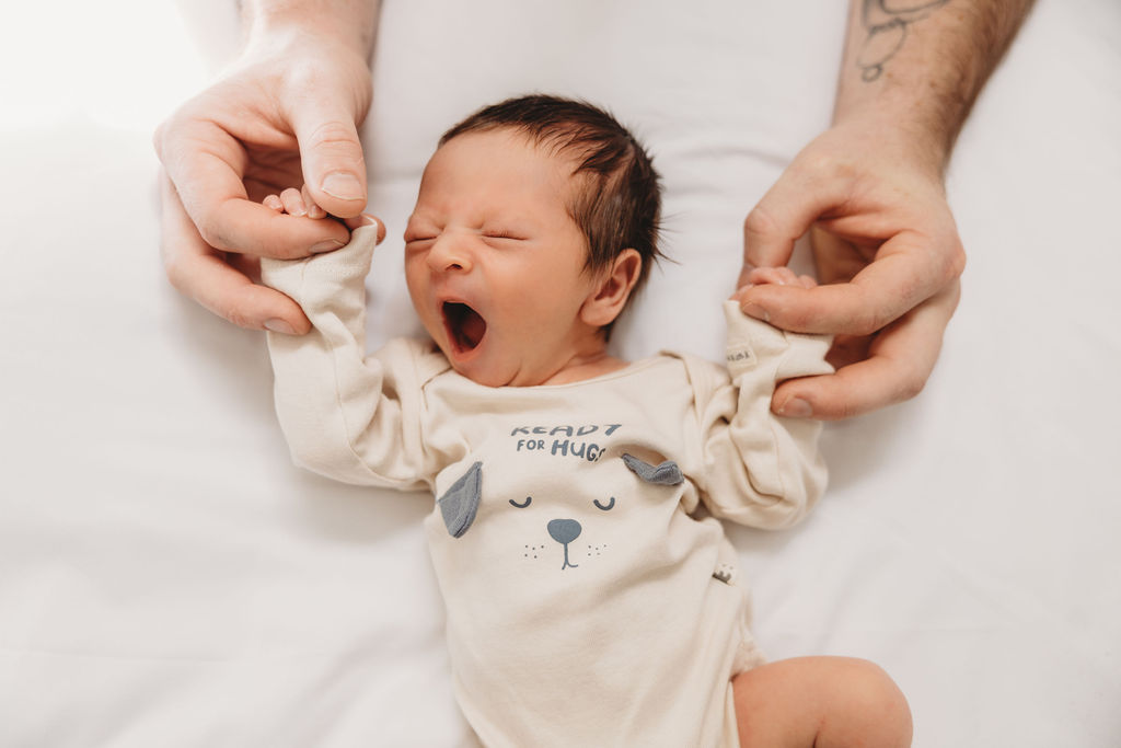 newborn baby yawning with brown onesie at newborn photo shoot 